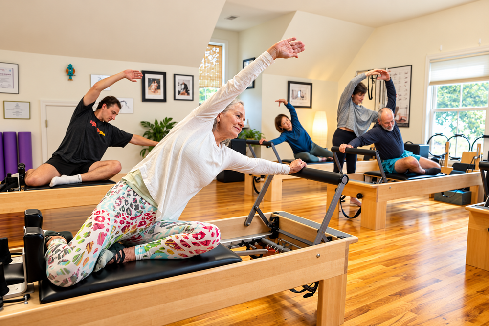 Clients practicing side stretches on reformers at Reichert Pilates of Summerville